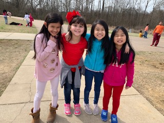 Four girls who are English Learner student stand with arms around each other on the playground